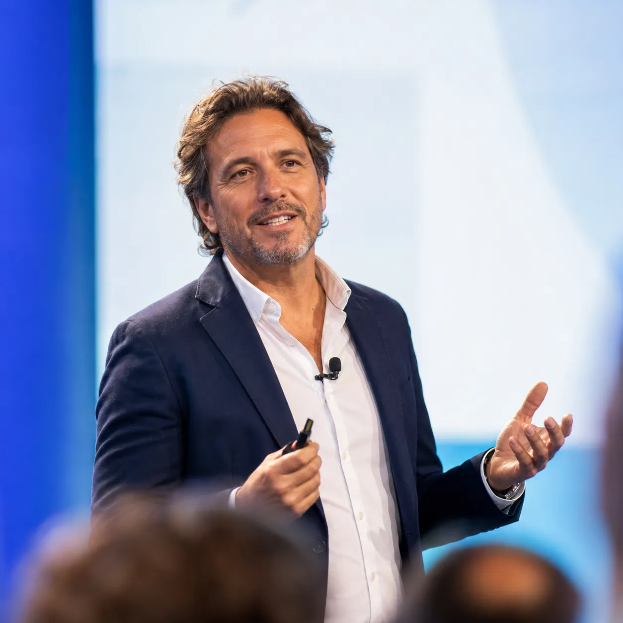 A confident speaker presenting on stage to an audience