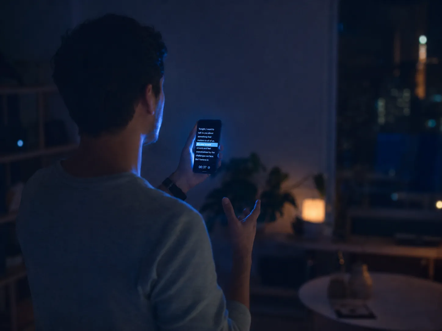 A man rehearsing his speech from a teleprompter on his phone at night